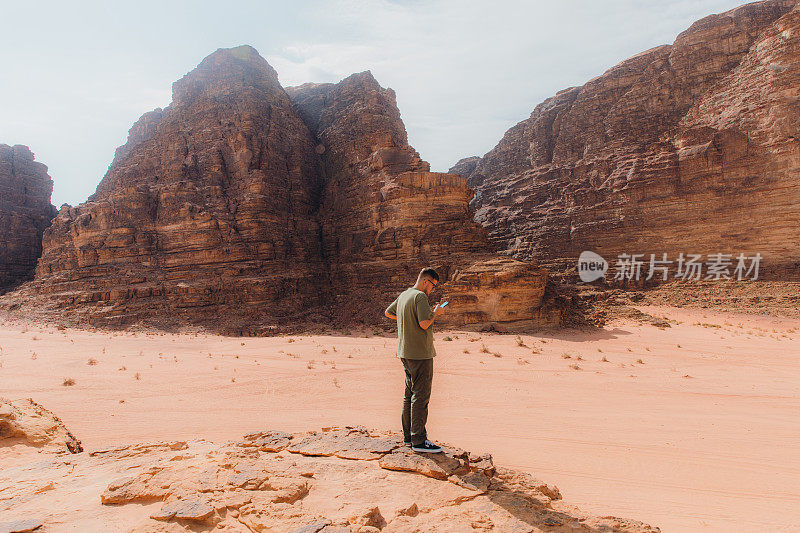 一名探险者通过智能手机发送了Wadi Rum沙漠风景的短信